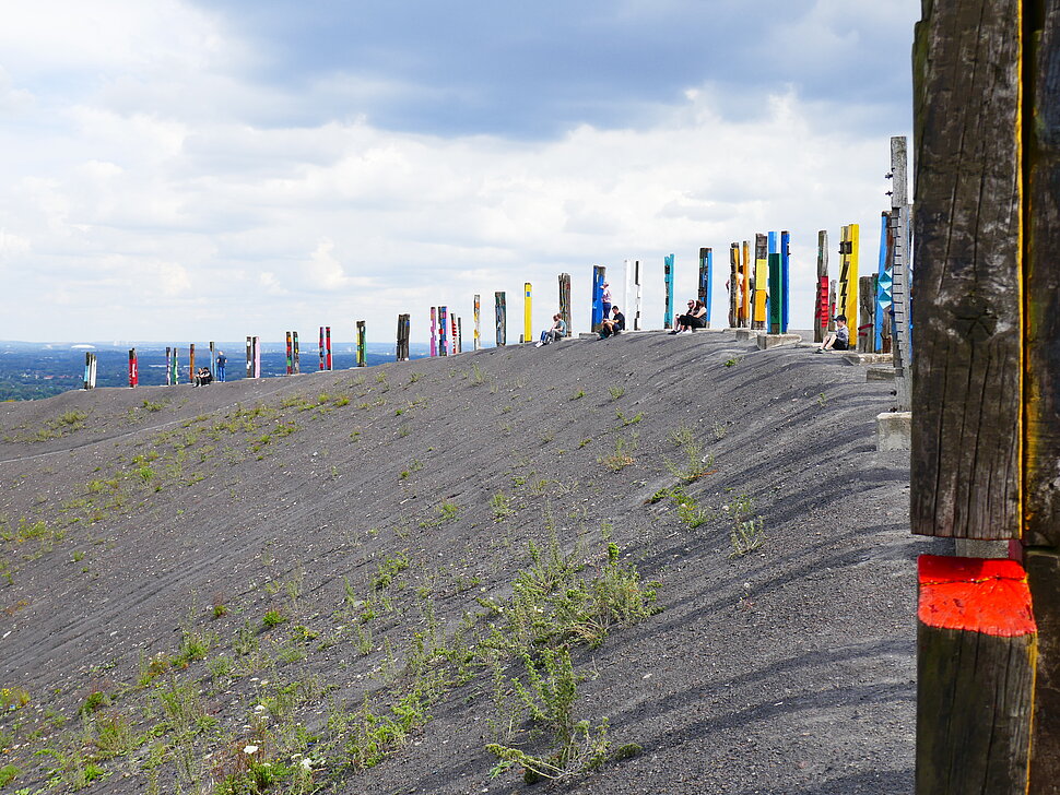 Unbewachsene Halde mit Kunstwerk aus Eisenbahnschwellen