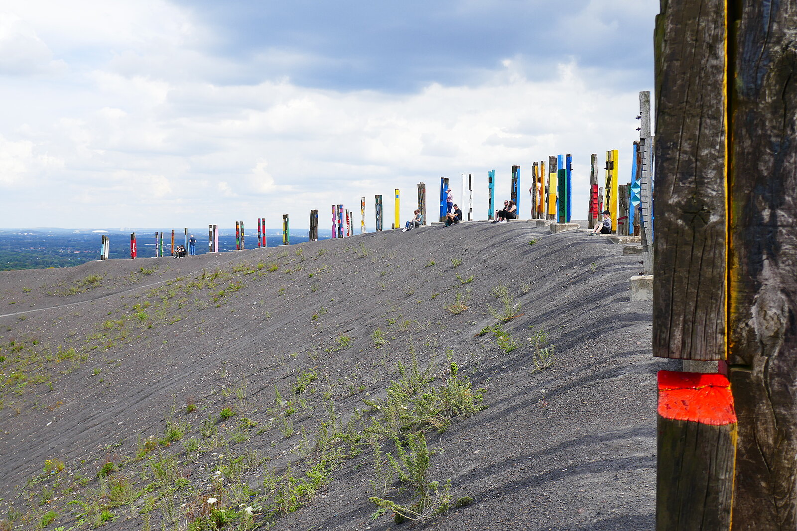 Unbewachsene Halde mit Kunstwerk aus Eisenbahnschwellen